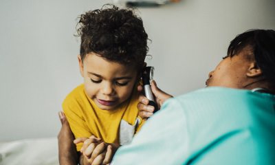 Caregiver taking child's temperature with ear thermometer.